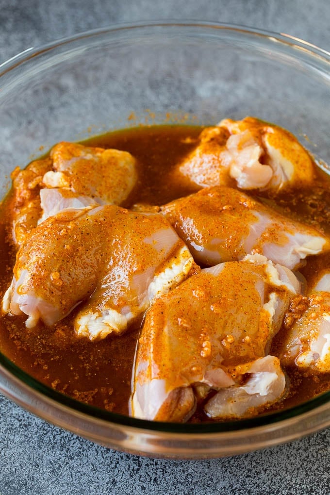 Chicken thighs in a bowl of marinade.