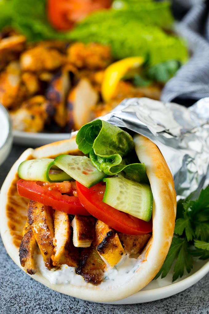 Chicken shawarma with lettuce and tomatoes, wrapped in pita bread.