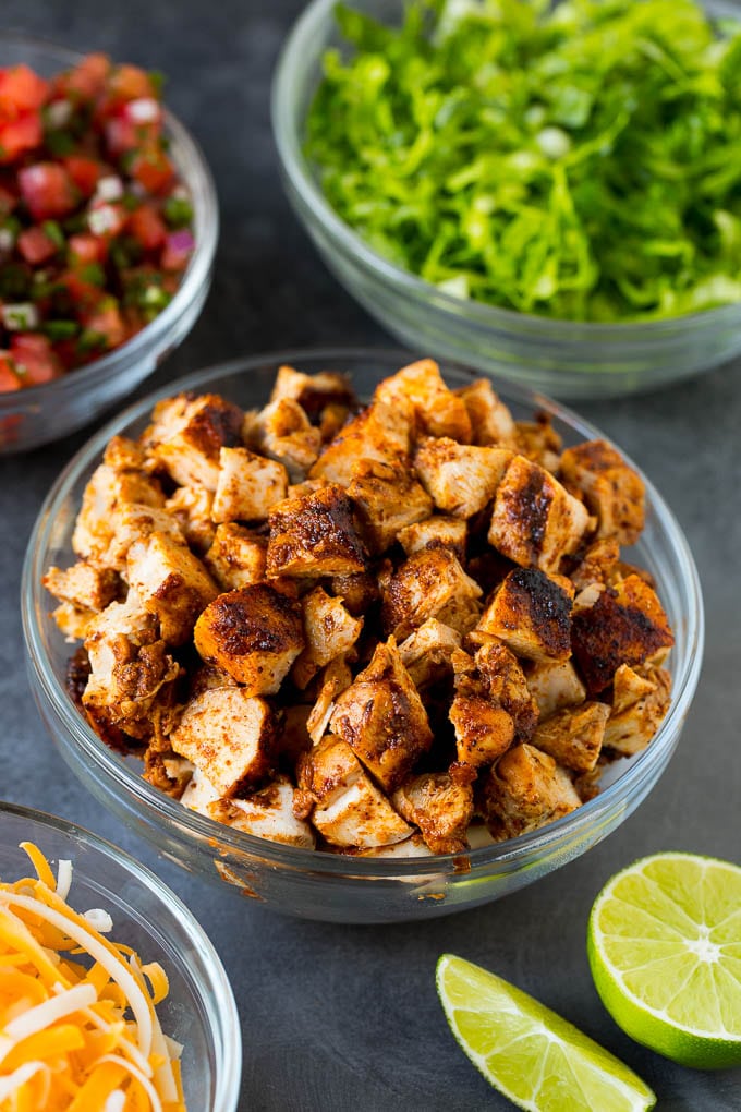 Diced chicken, shredded lettuce, salsa and cheese in bowls.