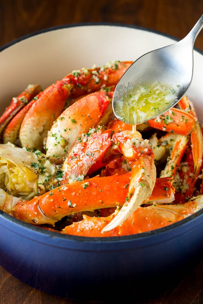 A spoon pouring garlic butter over cooked crab.