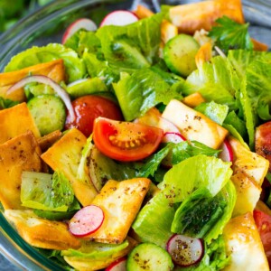 A bowl of fattoush salad with tomatoes, radishes and pita chips.