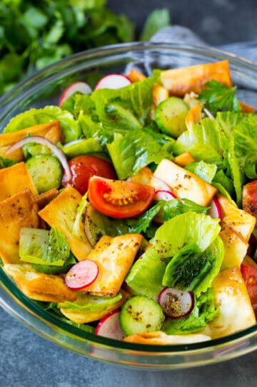 A bowl of fattoush salad with tomatoes, radishes and pita chips.