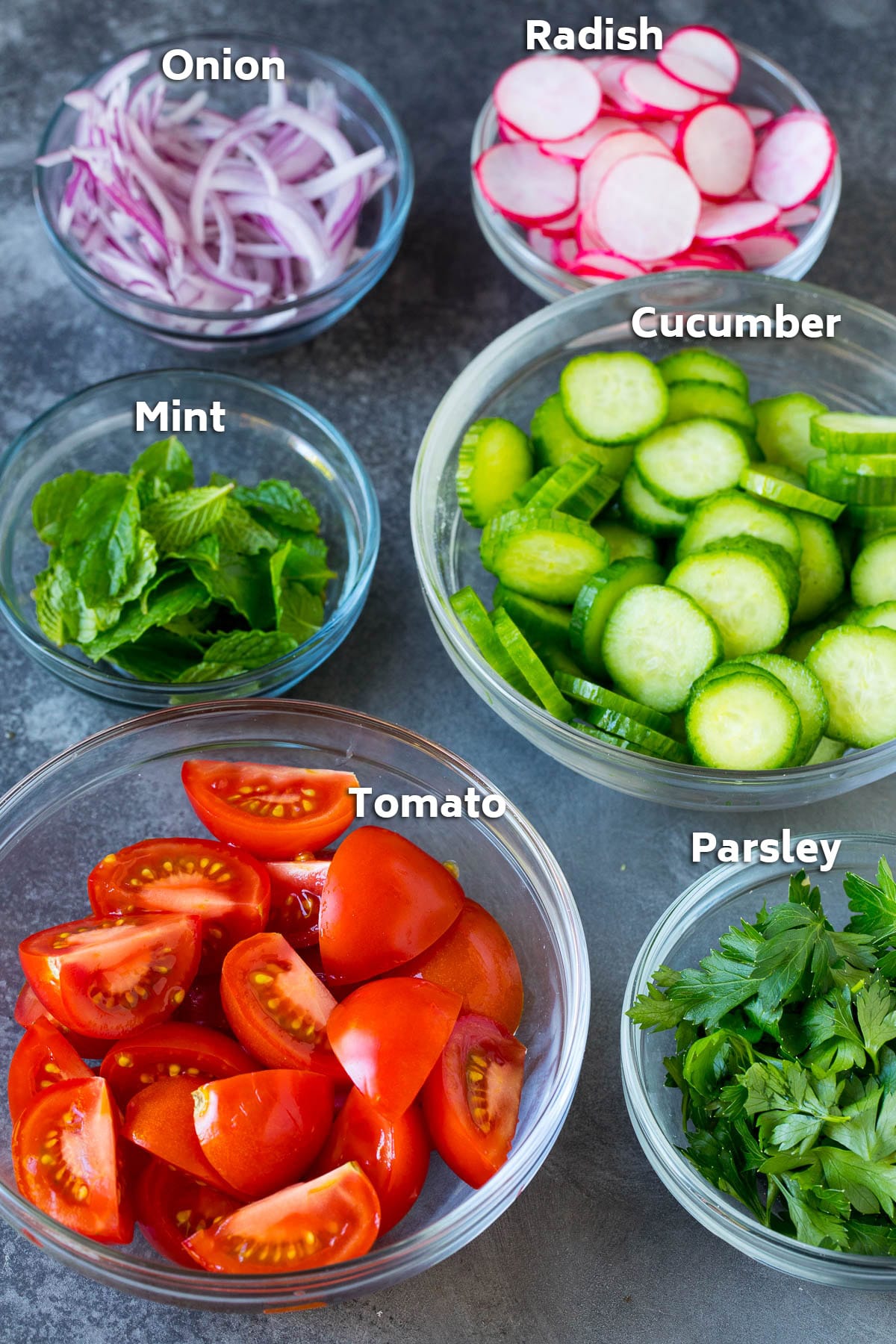 Glass bowls filled with vegetables and herbs.