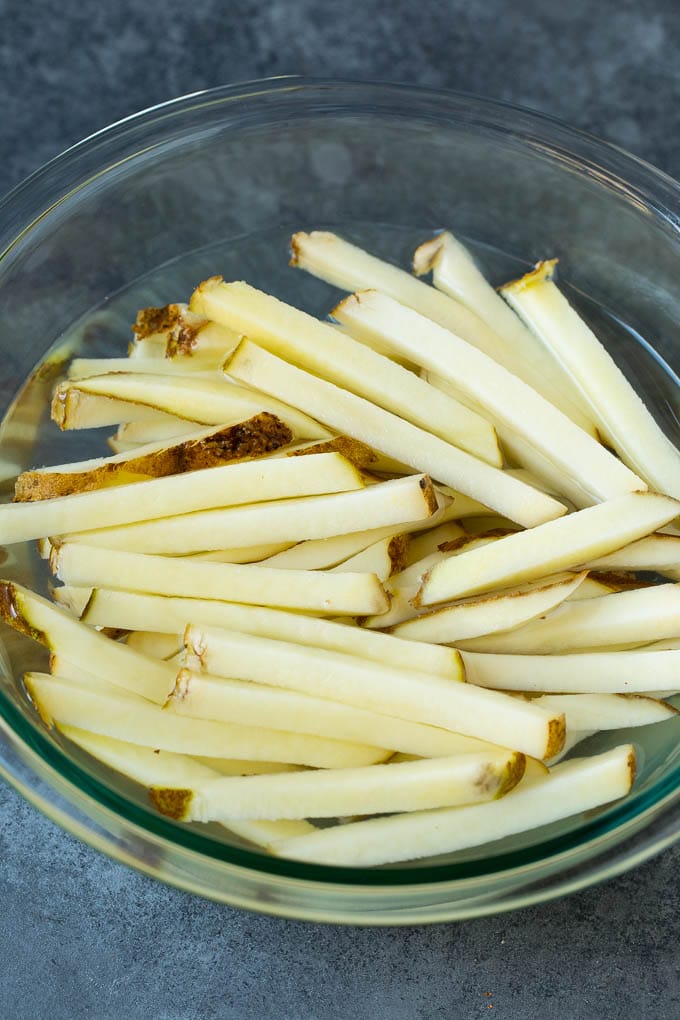 Sliced potato sticks in a bowl of water.