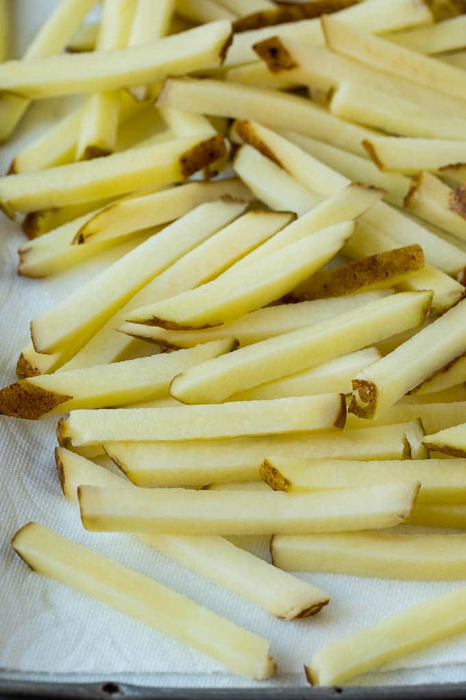 Potatoes cut into fry shapes on a paper towel lined pan.