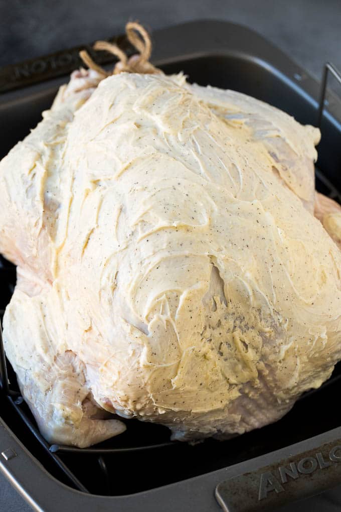 A raw turkey coated in seasoned butter.