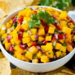 A bowl of mango salsa served with tortilla chips.