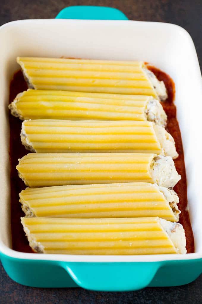 Pasta tubes stuffed with sausage and cheese in a baking dish.