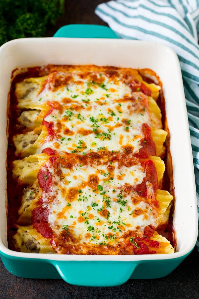 A dish of baked manicotti pasta topped with melted cheese and parsley.