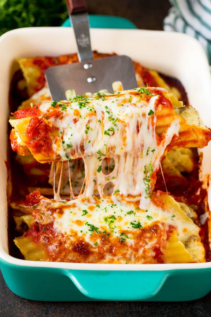 A spatula serving up a portion of baked manicotti pasta.