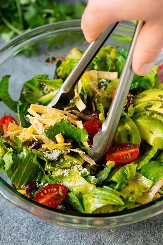 Tongs serving up a portion of Mexican salad.