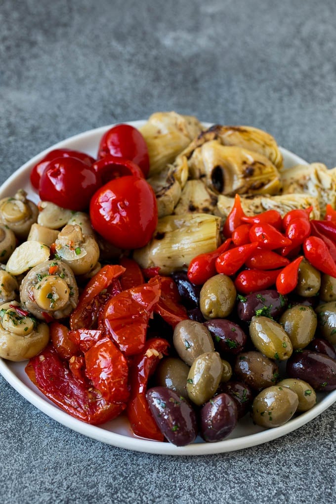 A plate of olives, peppers and grilled artichokes.