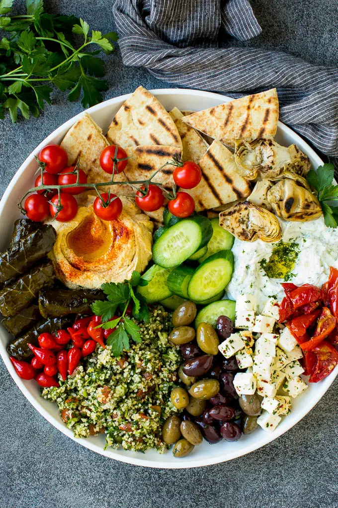 A mezze platter filled with dips, pita bread, vegetables, olives and cheese.