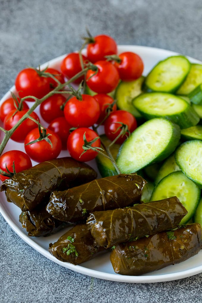 A plate of cherry tomatoes, cucumber slices and dolmas.