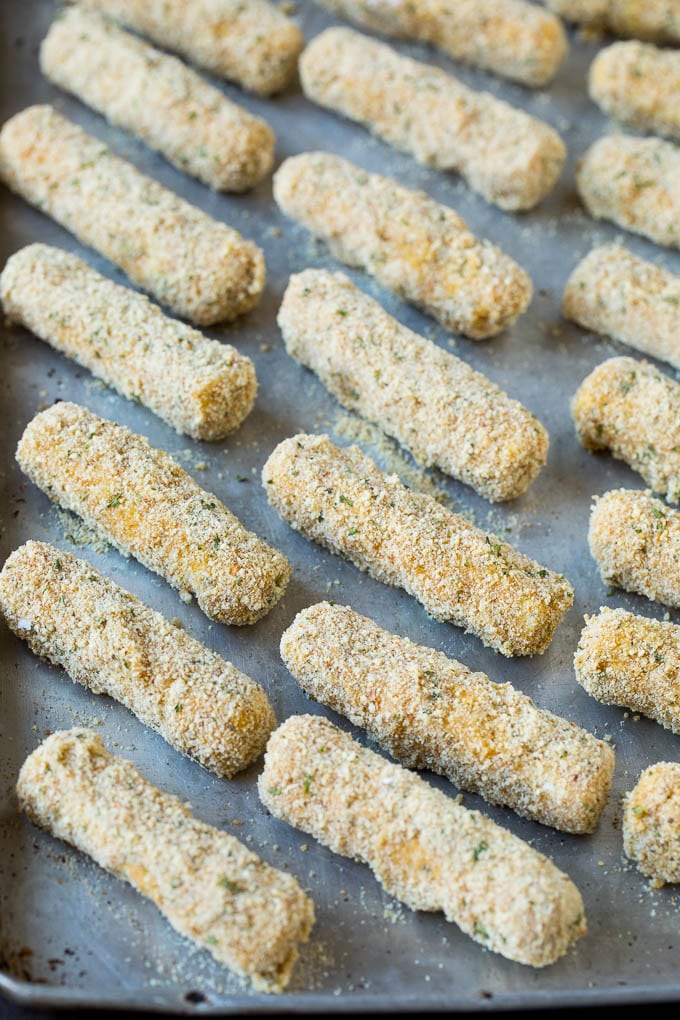 Breaded cheese sticks on a baking pan.
