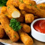 Mozzarella sticks served with a side of marinara sauce.