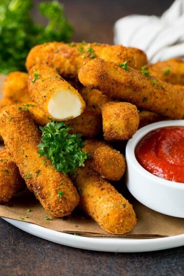 Mozzarella sticks served with a side of marinara sauce.