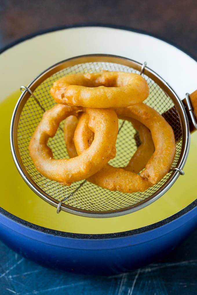 Fried onions coming out of a pot of oil.