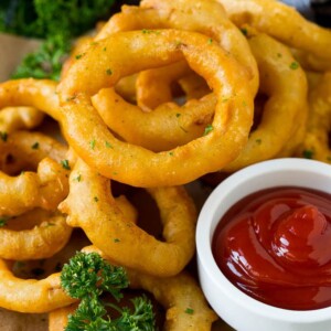 Fried onion rings on a plate with a side of ketchup.