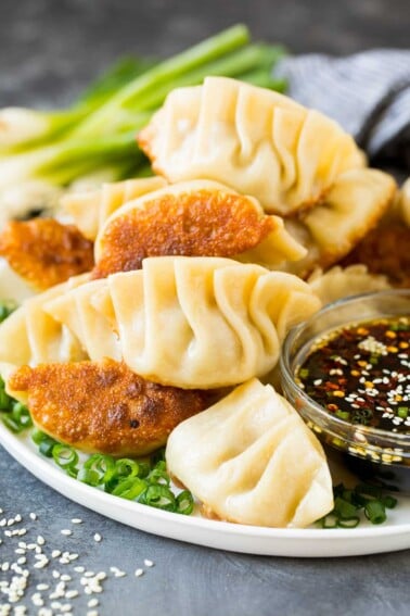 A plate of potstickers served with dipping sauce.