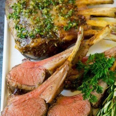 A platter of rack of lamb garnished with fresh herbs.