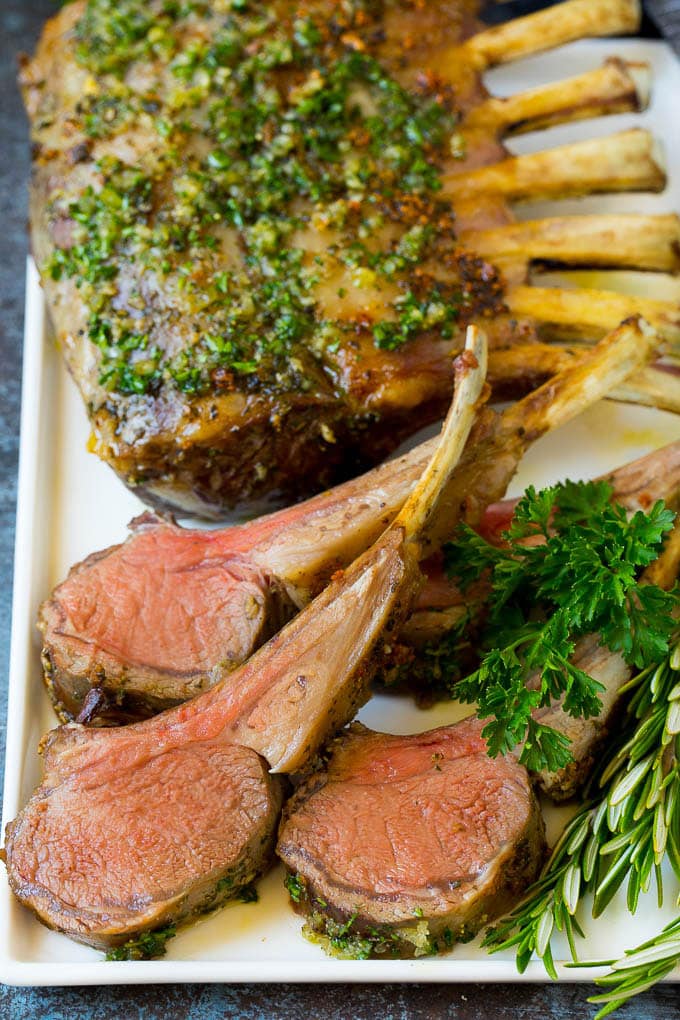 A platter of rack of lamb garnished with fresh herbs.