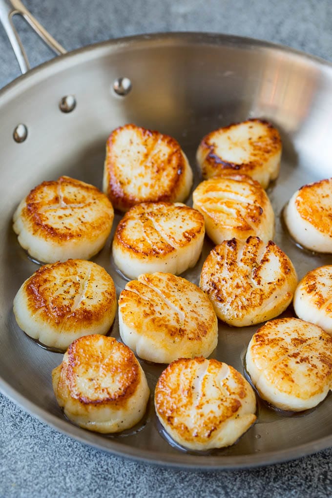 Scallops cooked to golden brown in a pan.