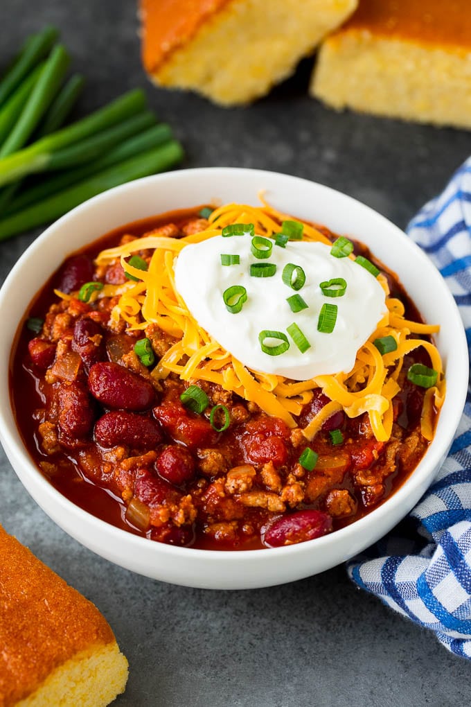 A bowl of turkey chili topped with cheese, sour cream and green onions.