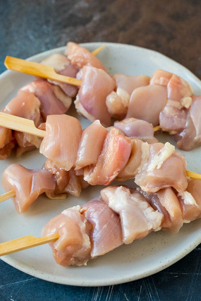 Raw chicken threaded onto skewers.