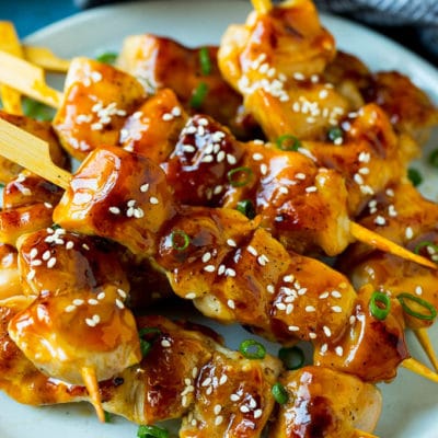 A plate of grilled chicken yakitori topped with sesame seeds and green onions.