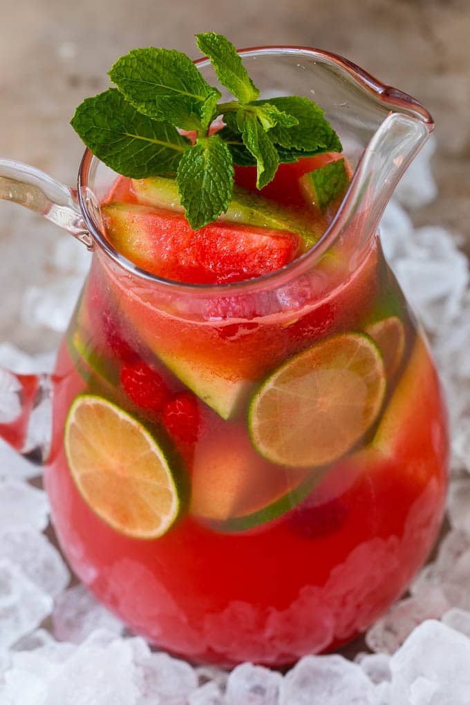 A pitcher of agua fresca garnished with limes and mint.
