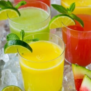 Cups of agua fresca in assorted fruit flavors.