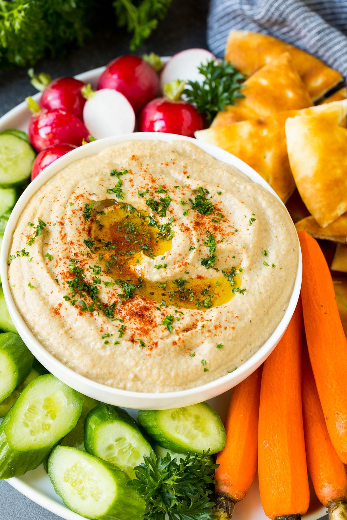 Baba ganoush in a bowl surrounded by bread and vegetables.