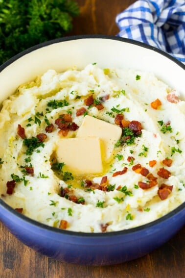 A pot of colcannon garnished with butter, bacon and herbs.