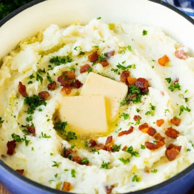 A pot of colcannon garnished with butter, bacon and herbs.
