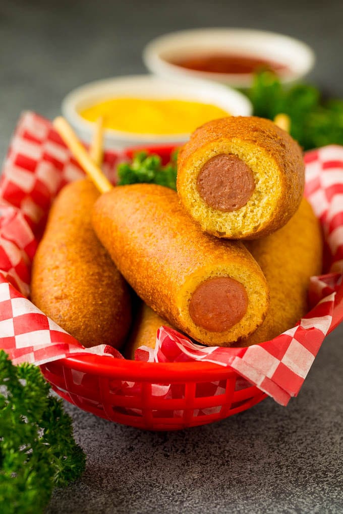 A basket of corn dogs with two of them cut open.