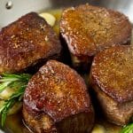 Filet mignon steaks topped with garlic butter and garnished with fresh rosemary.