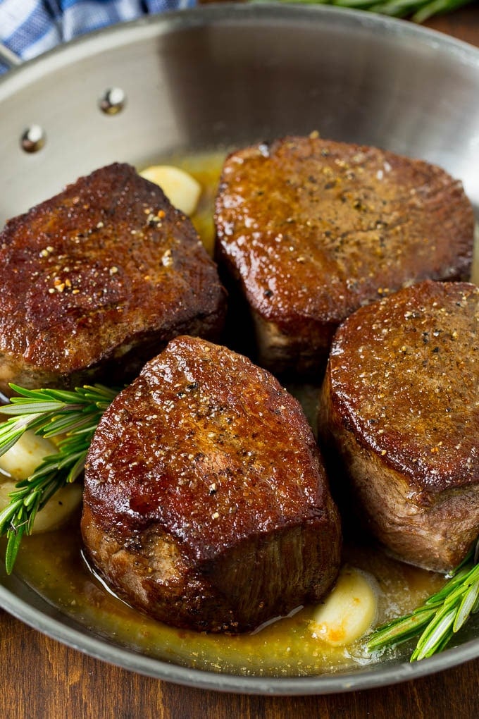 Filet mignon steaks topped with garlic butter and garnished with fresh rosemary.