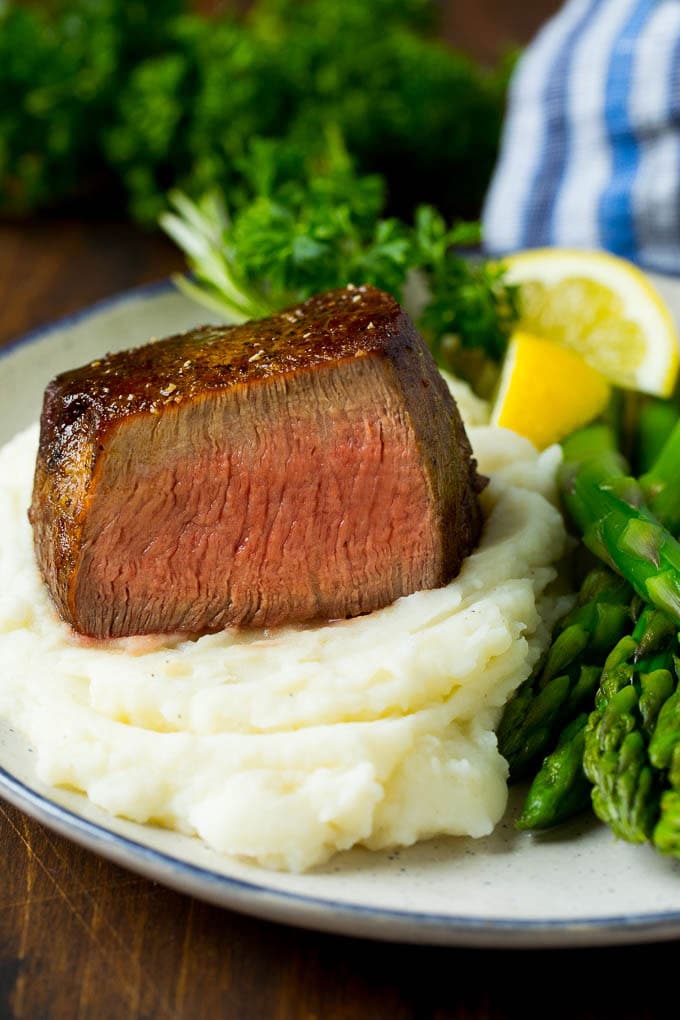 A cut filet mignon steak served with mashed potatoes and asparagus.