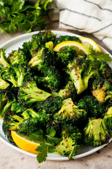 Grilled broccoli topped with parsley and garnished with lemon wedges.