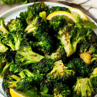 Grilled broccoli topped with parsley and garnished with lemon wedges.