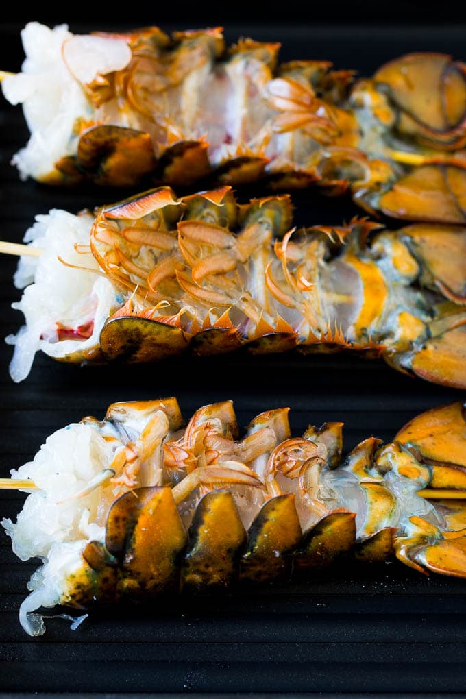 Lobster tails upside down on a grill pan.