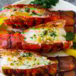 Grilled lobster tail topped with garlic butter and garnished with lemon and parsley.
