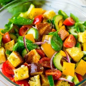 Panzanella salad with toasted bread cubes and fresh vegetables, all tossed in dressing.