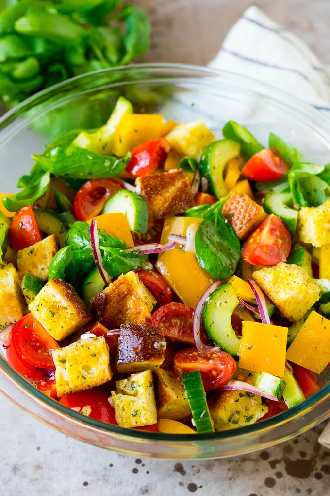 Panzanella salad with toasted bread cubes and fresh vegetables, all tossed in dressing.