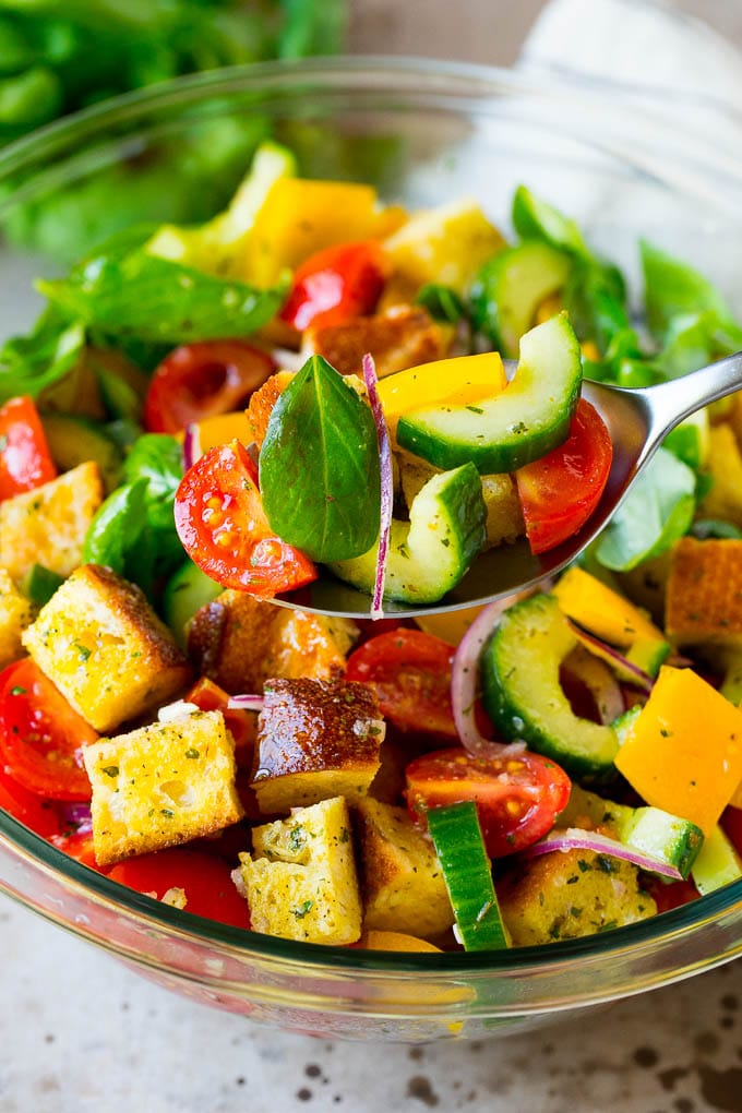 A spoon serving up a portion of panzanella salad.