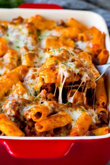 A spoon serving up a portion of Pasta al Forno with rigatoni and sausage.