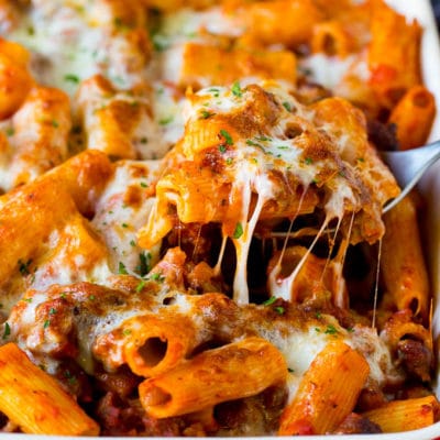 A spoon serving up a portion of Pasta al Forno with rigatoni and sausage.