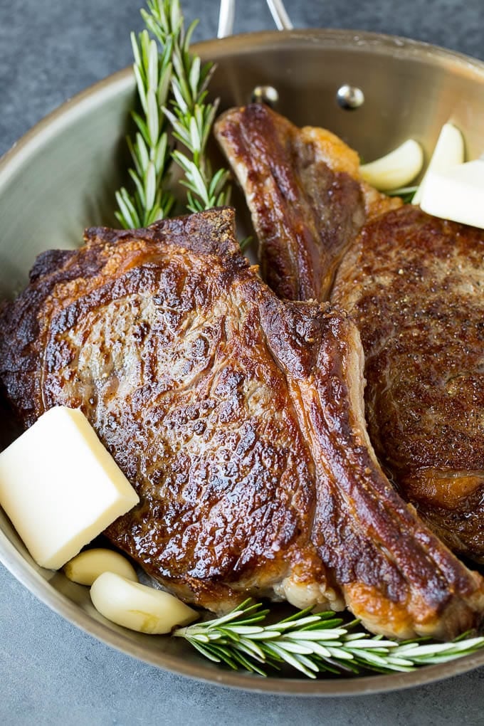 Steak with garlic, butter and rosemary sprigs.