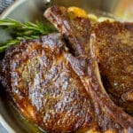 Rib eye steak with garlic butter and rosemary in a skillet.